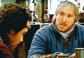 a man in a blue jacket is talking to another man in a dark room