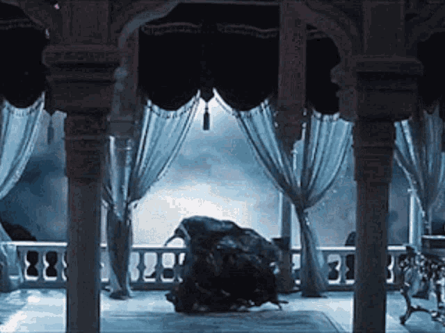 a room with columns and blue curtains and a person standing in the middle