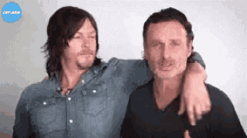 two men are standing next to each other and one of them is hugging the other .