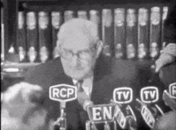 a man in a suit is speaking into a microphone with rcp tv and en written on it