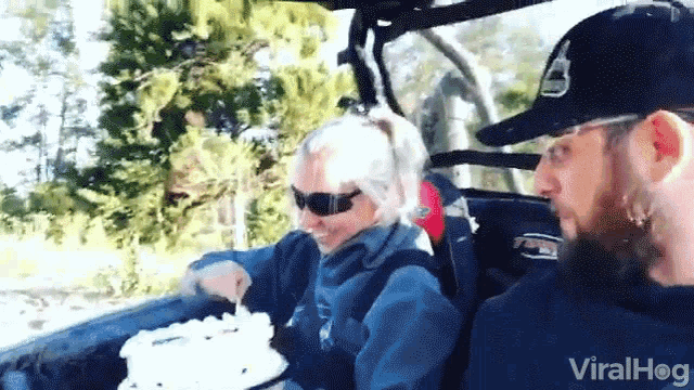 a man and a woman are in a vehicle with a cake in the back .