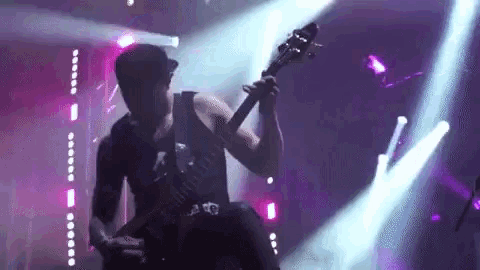a man is playing a guitar on a stage in front of a crowd .