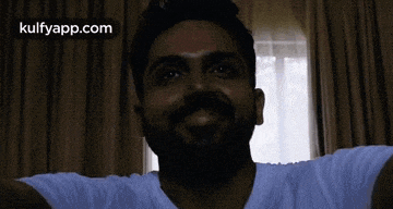 a man with his arms outstretched is smiling in front of a window with the words kulfyapp.com on the bottom