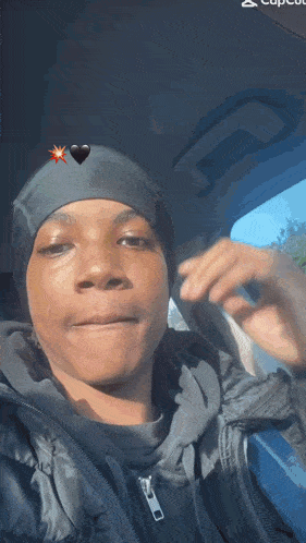 a young man is sitting in a car wearing a black beanie