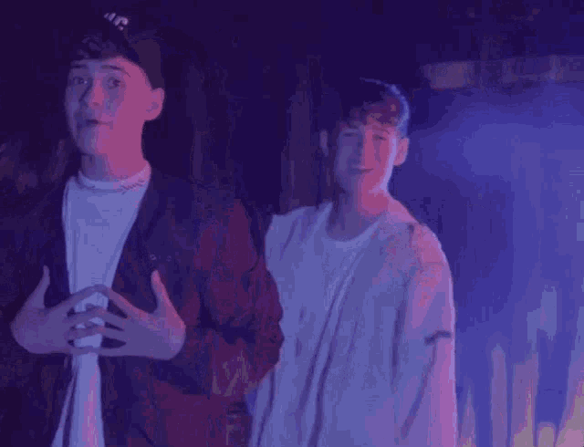 two young men are standing next to each other in front of a purple background