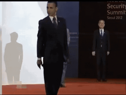 a man in a suit and tie stands in front of a sign that says security summit