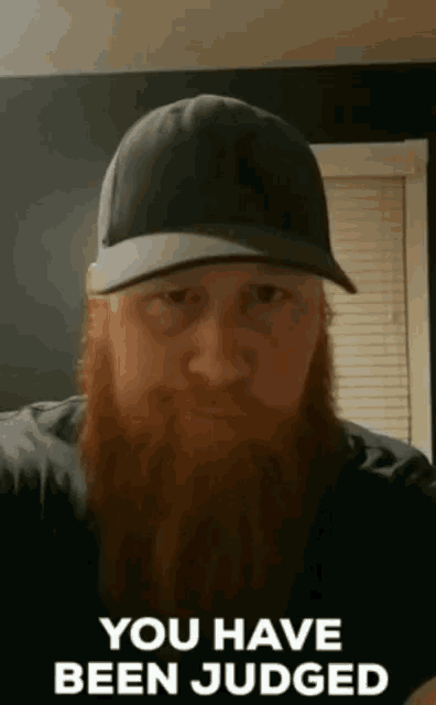 a man with a long beard wearing a hat says " you have been judged "