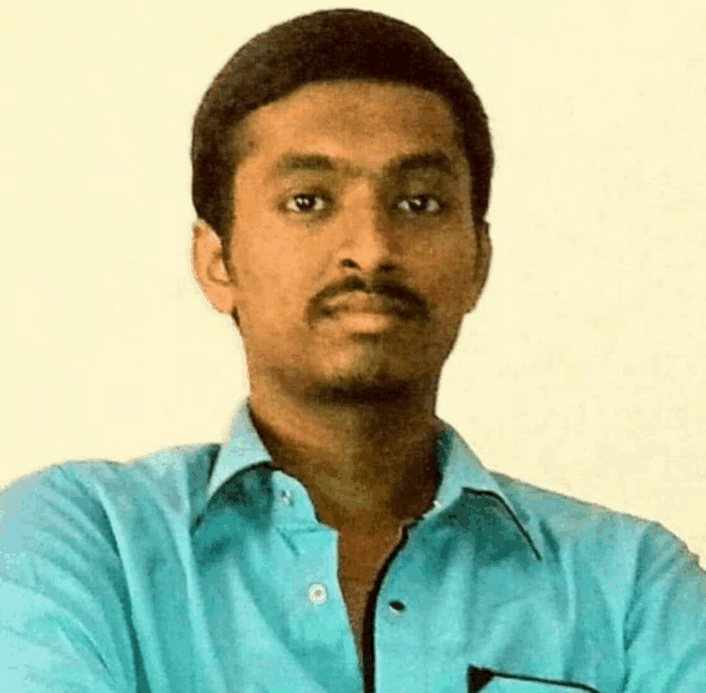 a man in a blue shirt is looking at the camera with his arms crossed