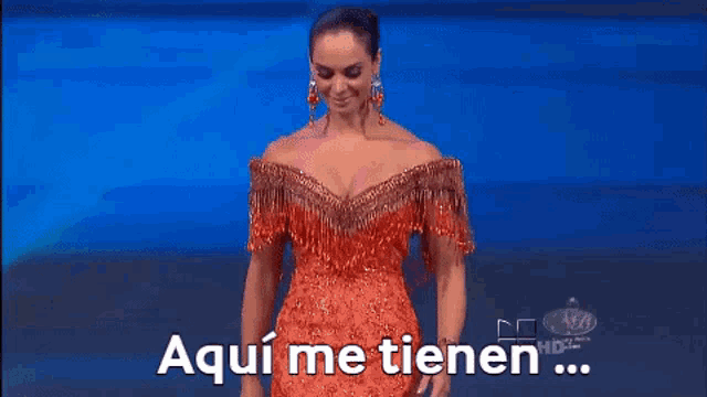 a woman in a red dress is standing on a stage and says aqui me tienen ...