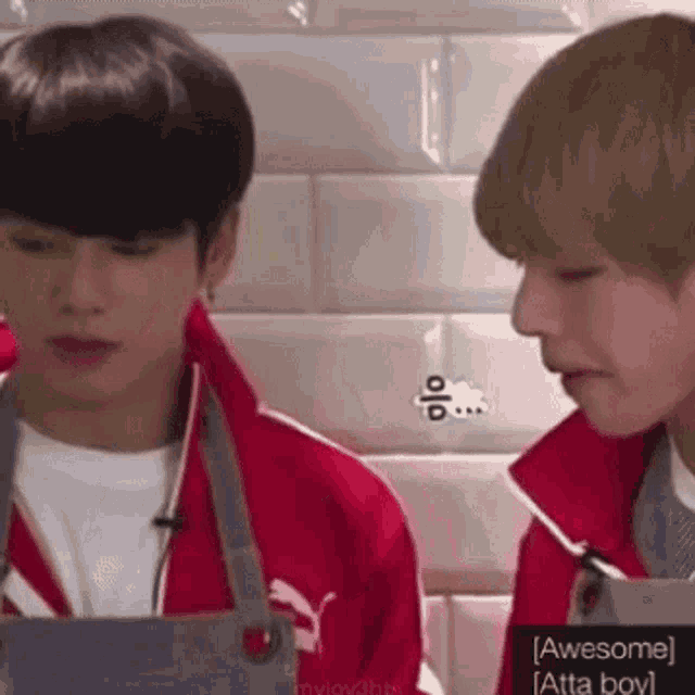 a couple of young men are standing next to each other in a kitchen .