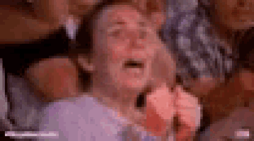 a woman is sitting in a crowd of people with her mouth open and a shocked look on her face .