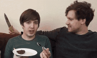 a man is holding a knife while another man is holding a plate of food .
