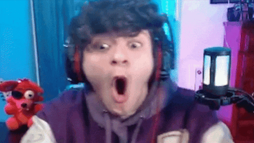 a young man wearing headphones and a purple jacket is making a surprised face .