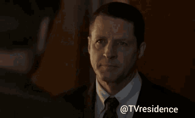 a man is looking at another man in a dark room with the words tvresidence written on the bottom