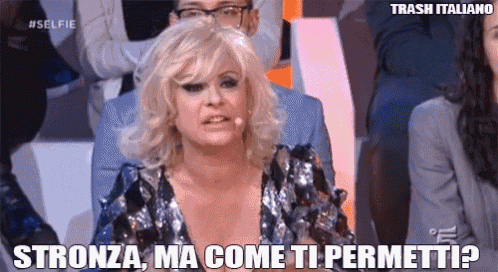 a woman is sitting in a crowd and says stronza ma come ti permetti ?