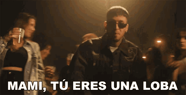 a man wearing sunglasses stands in front of a group of women with the words mami tu eres una loba written below him