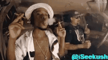 a man is smoking a cigarette in a car while another man watches .