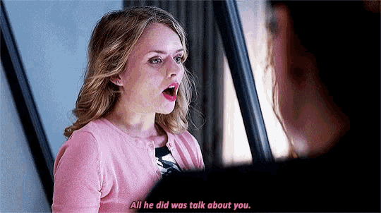 a woman in a pink sweater is talking to another woman in a mirror .