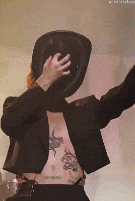 a man covering his face with a hat has a tattoo on his stomach that says mariomania