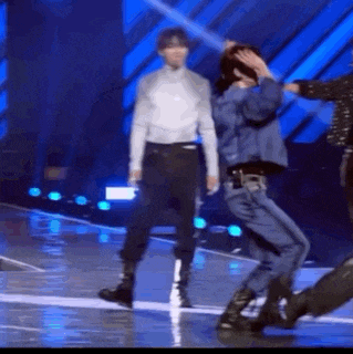 a group of men are dancing on a stage in front of a crowd .