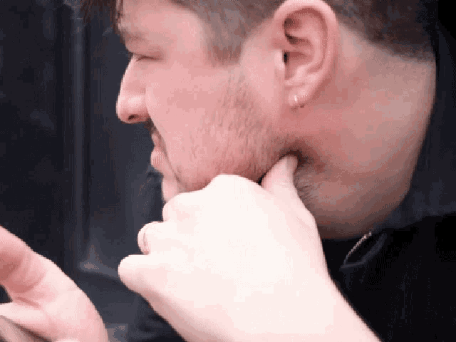 a man with a beard and ear piercings looks down at something
