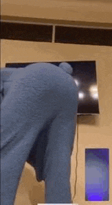a person in a blue teddy bear costume is standing in front of a tv .