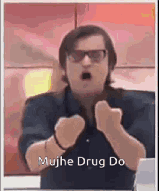 a man wearing sunglasses and a black shirt is making a funny face with his fist up .
