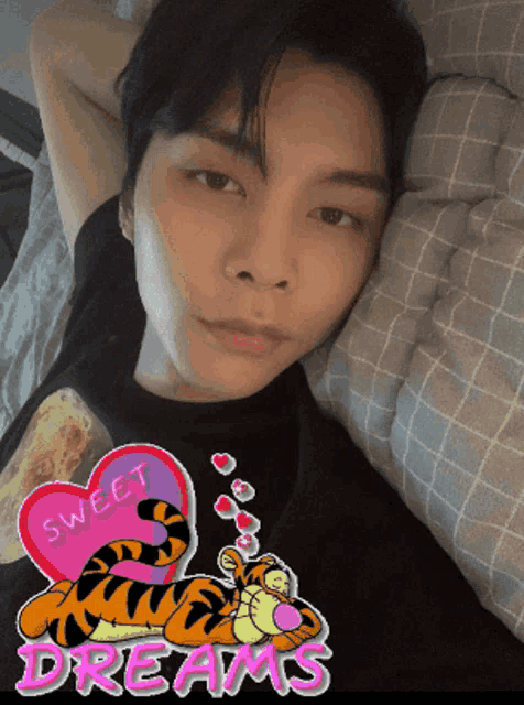 a man laying on a bed with a tigger and a heart that says sweet dreams on it