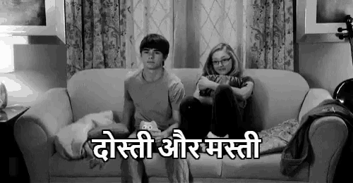 a boy and a girl are sitting on a couch watching a movie .