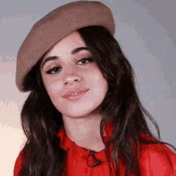 a woman wearing a beret and a red shirt is smiling for the camera .