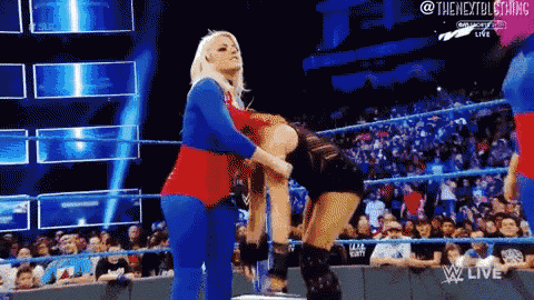 a woman in a superhero costume holds another woman in a wrestling ring .
