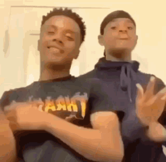 two young men are standing next to each other in a room .