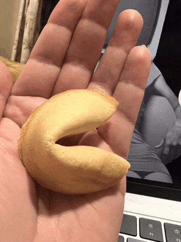 a person is holding a fortune cookie in front of a keyboard