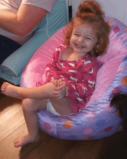 a little girl is sitting on a purple bean bag chair