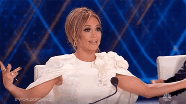 a woman in a white cape is sitting in front of a microphone .