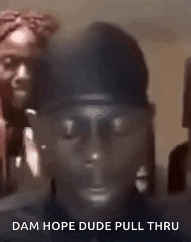 a man with a mask on his face is standing in front of a group of people and says dam hope dude pull thru .