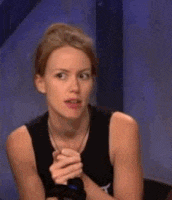 a woman in a black tank top is sitting in front of a blue wall .
