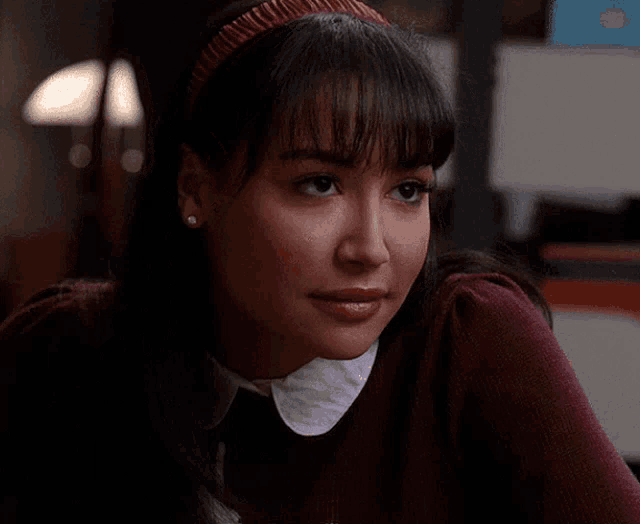 a woman wearing a red headband and a maroon sweater