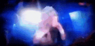 a blurry image of a person standing in front of a blue light