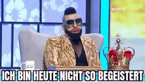 a man with a beard and sunglasses is sitting in a chair .