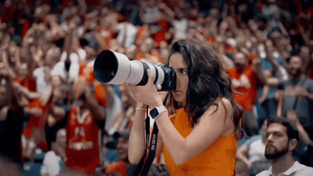 a woman is holding a canon camera in front of a crowd