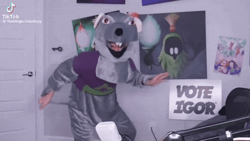 a man in a chuck e cheese costume is dancing in front of a sign that says vote igor