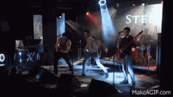 a band is performing on stage in front of a sign that says " steel "