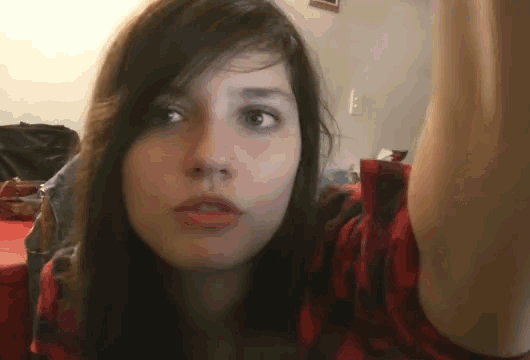 a girl in a red and black plaid shirt is looking at the camera
