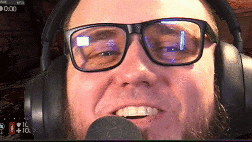 a man wearing glasses and headphones is smiling in front of a microphone