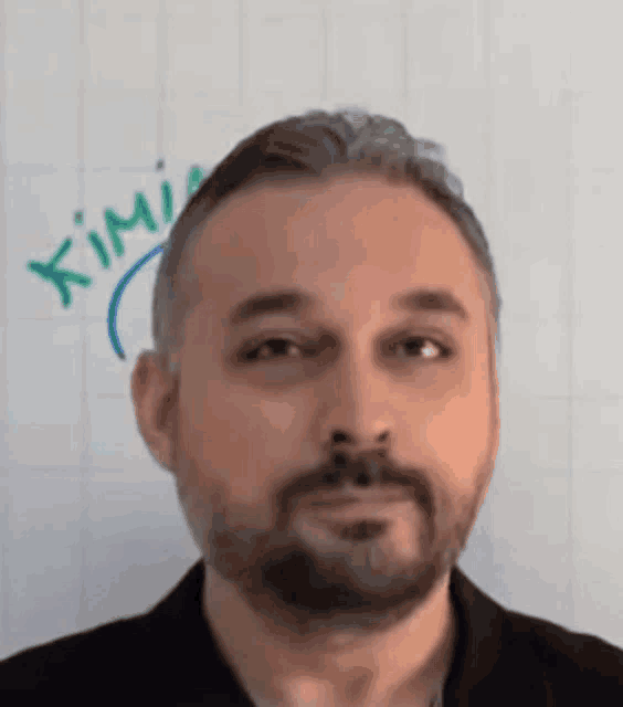 a man with a beard is standing in front of a whiteboard that says kimia .