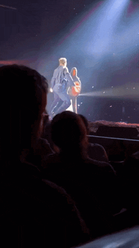 a man is playing a guitar on a stage while a woman stands behind him