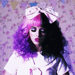 a woman with purple and black hair has a pink bow on her head