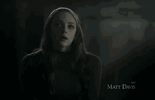 a woman in a dark room with the name matt davis on the bottom right