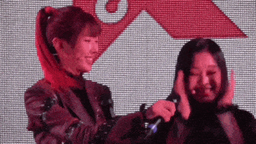 two women are standing next to each other on a stage and one of them is holding the other 's hair .